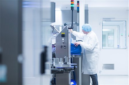 Worker operating machinery on production line in pharmaceutical plant Foto de stock - Sin royalties Premium, Código: 649-08923025