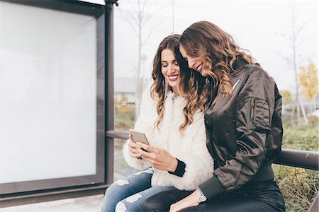 simsearch:649-08923050,k - Twin sisters sitting outdoors, looking at smartphone Stock Photo - Premium Royalty-Free, Code: 649-08923063