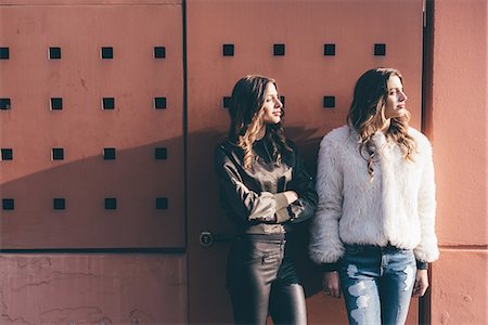 simsearch:649-08923095,k - Portrait of twin sisters, outdoors, leaning against wall, looking away Foto de stock - Royalty Free Premium, Número: 649-08923093