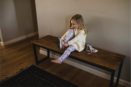 Girl sitting on bench putting on trainer shoe Photographie de stock - Premium Libres de Droits, Code: 649-08923113