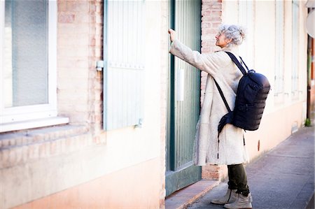 Mature woman pressing front door bell in local french village Stock Photo - Premium Royalty-Free, Code: 649-08923288