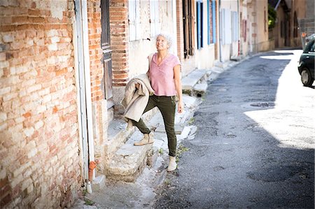 simsearch:649-08924077,k - Woman in street looking away smiling, Bruniquel, France Photographie de stock - Premium Libres de Droits, Code: 649-08923306