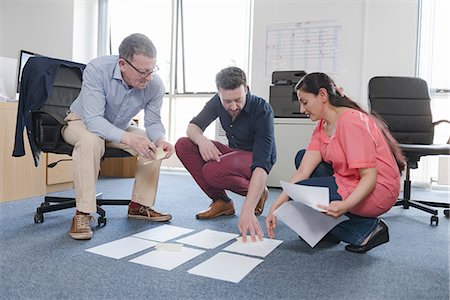 Colleagues discussing papers on office floor Stock Photo - Premium Royalty-Free, Code: 649-08923652