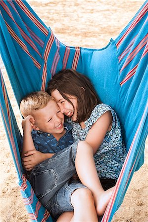family ,huddle - Girl and brother laughing huddled in hammock on Poetto beach, Cagliari, Italy Foto de stock - Sin royalties Premium, Código: 649-08923705
