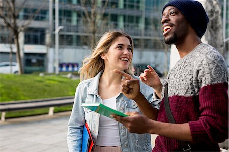 diversity in college campuses - Young couple walking outdoors, holding notebooks, smiling Stock Photo - Premium Royalty-Free, Code: 649-08923751
