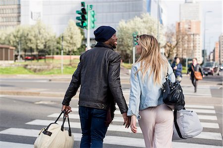 simsearch:649-08923913,k - Young couple crossing road, carrying holdalls, rear view, smiling Stock Photo - Premium Royalty-Free, Code: 649-08923763