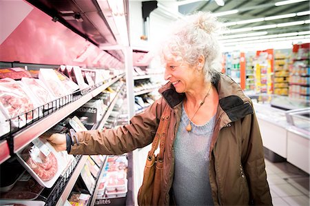 simsearch:649-08923766,k - Mature woman in supermarket, looking at chilled meat section Foto de stock - Royalty Free Premium, Número: 649-08923774