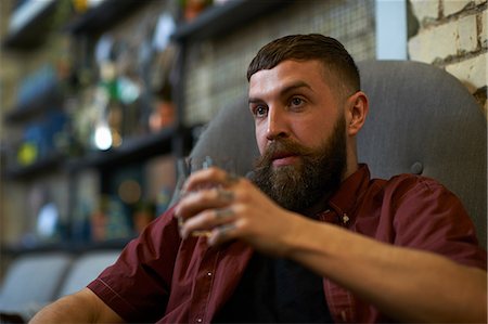 Young man with tattooed fingers holding tumbler of spirit in public house Stock Photo - Premium Royalty-Free, Code: 649-08923978