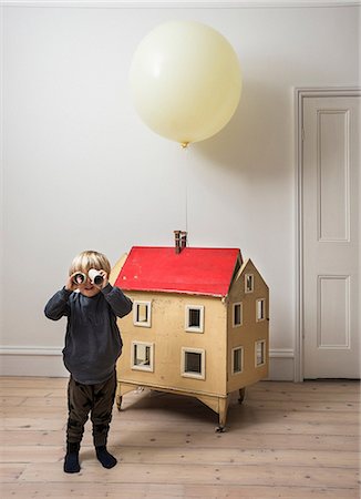 Boy standing beside dolls house looking through cardboard tube at camera Photographie de stock - Premium Libres de Droits, Code: 649-08949491