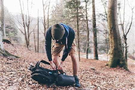 simsearch:649-08949532,k - Young male hiker unpacking backpack in forest, Monte San Primo, Italy Stock Photo - Premium Royalty-Free, Code: 649-08949548