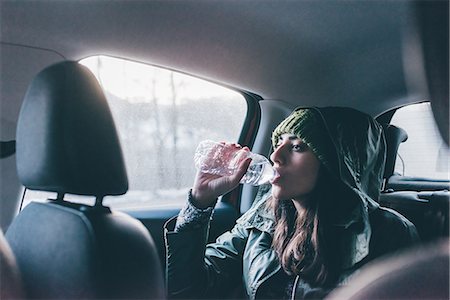 simsearch:649-08949542,k - Woman drinking water in back seat of car Photographie de stock - Premium Libres de Droits, Code: 649-08949558