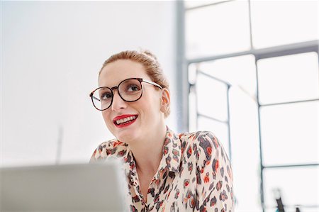 simsearch:649-08543194,k - Woman in office wearing reading glasses looking away smiling Foto de stock - Sin royalties Premium, Código: 649-08949621