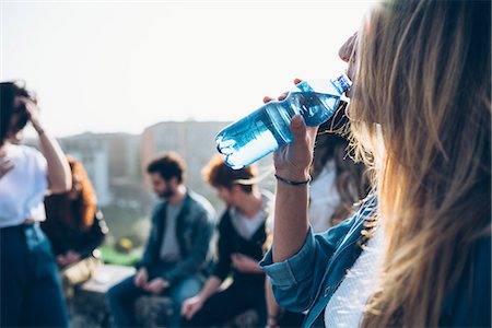 simsearch:649-08949675,k - Group of friends enjoying roof party, young woman drinking from water bottle Foto de stock - Sin royalties Premium, Código: 649-08949666