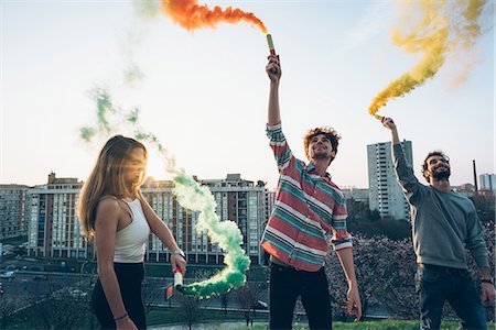 simsearch:649-08949675,k - Group of friends on roof, holding colourful smoke flares Foto de stock - Sin royalties Premium, Código: 649-08949688