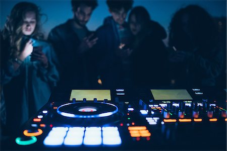 simsearch:649-08949675,k - Group of people at roof party, standing around illuminated mixing desks Foto de stock - Sin royalties Premium, Código: 649-08949718