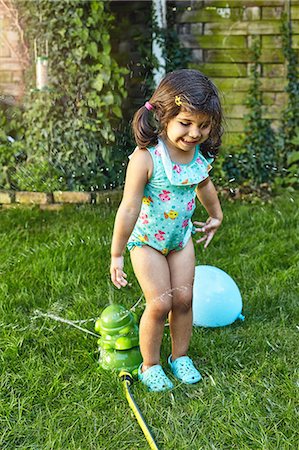 simsearch:649-08578165,k - Young girl playing in garden, beside water sprinklers Stock Photo - Premium Royalty-Free, Code: 649-08949734