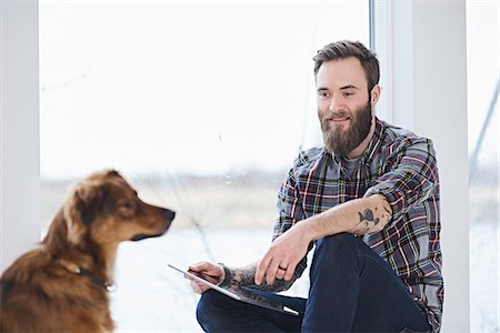 small business owner with tablet - Young male designer with dog in design studio window seat Foto de stock - Sin royalties Premium, Código: 649-08949784