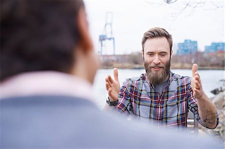 Over shoulder view of male designers having discussion on waterfront outside design studio Stock Photo - Premium Royalty-Free, Code: 649-08949789