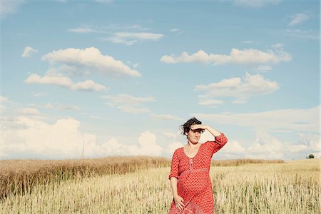 Pregnant woman in wheat field shielding her eyes Stock Photo - Premium Royalty-Free, Code: 649-08949904