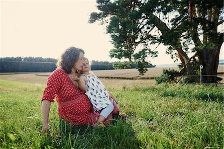 Pregnant woman sitting in field with toddler daughter on lap Stock Photo - Premium Royalty-Free, Code: 649-08949900