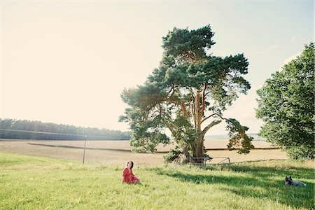 Distant view of pregnant woman sitting in field landscape Photographie de stock - Premium Libres de Droits, Code: 649-08949902