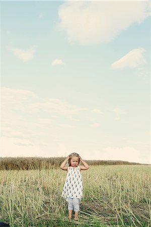 Female toddler standing in wheat field with hand in her hair Stock Photo - Premium Royalty-Free, Code: 649-08949912