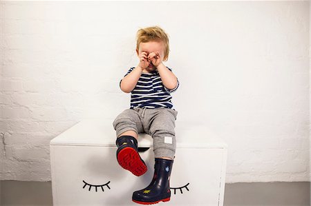 simsearch:649-07596283,k - Male toddler sitting on toy chest and rubbing his eyes Stock Photo - Premium Royalty-Free, Code: 649-08949964