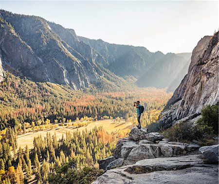 Man on rocky edge looking out through binoculars, Yosemite National Park, California, USA Stock Photo - Premium Royalty-Free, Code: 649-08950372