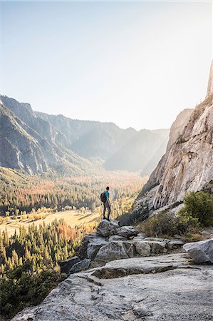 simsearch:614-07194672,k - Man on boulder looking out at valley forest, Yosemite National Park, California, USA Fotografie stock - Premium Royalty-Free, Codice: 649-08950373