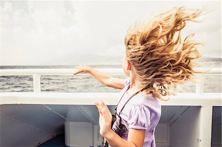 Young girl standing on boat, looking at view, wind blowing hair Stock Photo - Premium Royalty-Free, Code: 649-08950529