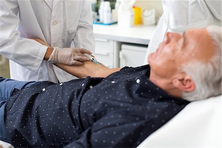 exames de sangue - Doctor extracting patient's blood with syringe Foto de stock - Royalty Free Premium, Número: 649-08950929