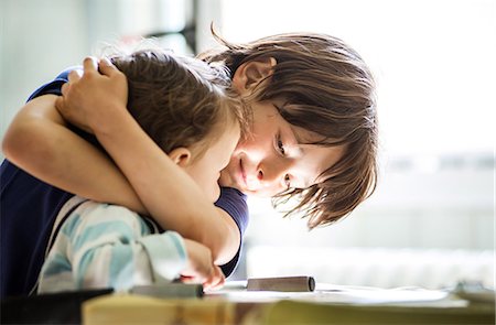 Boy at table hugging toddler brother Foto de stock - Royalty Free Premium, Número: 649-08951072