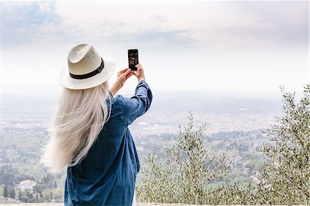 Rear view of mature woman with long grey hair photographing view, Fiesole, Tuscany, Italy Fotografie stock - Premium Royalty-Free, Codice: 649-08951136