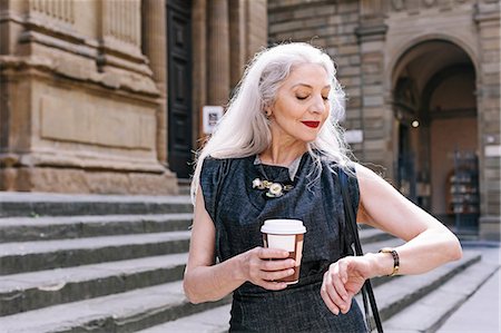 Mature woman with long grey hair looking at wristwatch in Florence, Italy Stock Photo - Premium Royalty-Free, Code: 649-08969115