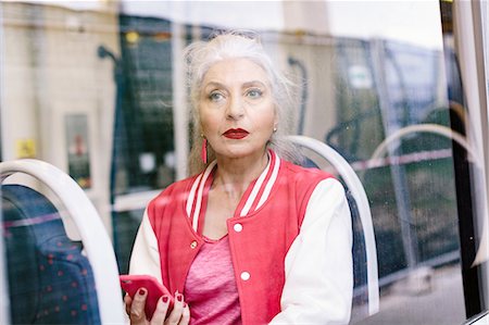 retro mobile phone - Mature woman in baseball jacket looking through window from bus Stock Photo - Premium Royalty-Free, Code: 649-08969124