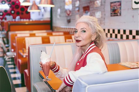 retro diner pictures - Portrait of mature woman in baseball jacket with milkshake in 1950's diner Stock Photo - Premium Royalty-Free, Code: 649-08969126