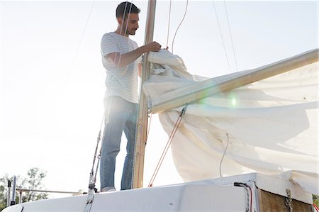 simsearch:649-08969325,k - Man on sailing boat, preparing to hoist sail Photographie de stock - Premium Libres de Droits, Code: 649-08969313