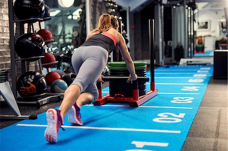 simsearch:649-07238781,k - Rear view of young woman training, pushing weight sled in gym Photographie de stock - Premium Libres de Droits, Code: 649-08969509
