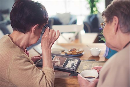 simsearch:649-07064439,k - Over shoulder view of two senior women looking at photo album on table Stock Photo - Premium Royalty-Free, Code: 649-08969516