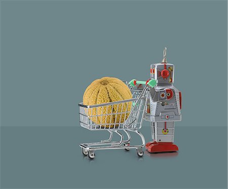 simsearch:614-06896427,k - Toy robot pushing miniature shopping trolley with melon against grey background Foto de stock - Sin royalties Premium, Código: 649-08969533