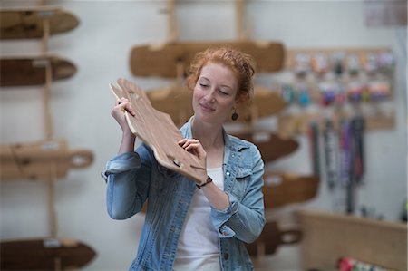 Woman working in skateboard shop, inspecting wooden board Stock Photo - Premium Royalty-Free, Code: 649-08969571