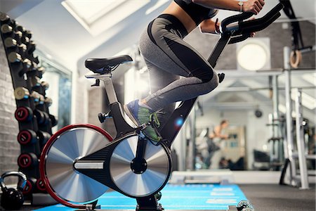 simsearch:649-09111299,k - Neck down view of young woman training, pedalling exercise bike in gym Foto de stock - Sin royalties Premium, Código: 649-08969583