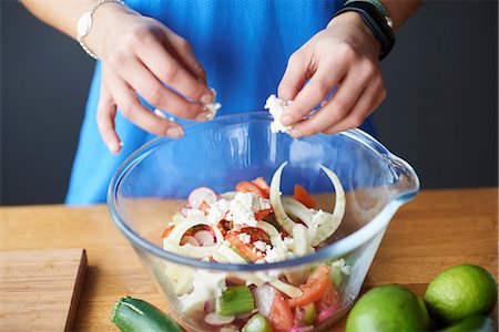 people nutrition - Hands of young woman at kitchen table crumbling feta into salad bowl Stock Photo - Premium Royalty-Free, Code: 649-08969605