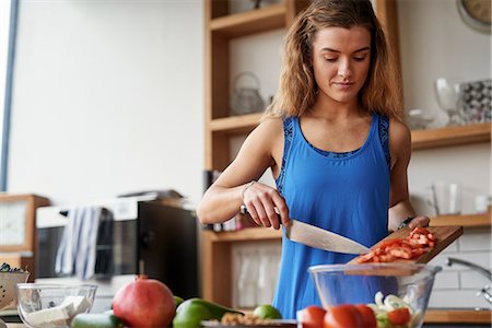 simsearch:649-08422922,k - Young woman at kitchen table slicing tomatoes Stock Photo - Premium Royalty-Free, Code: 649-08969600