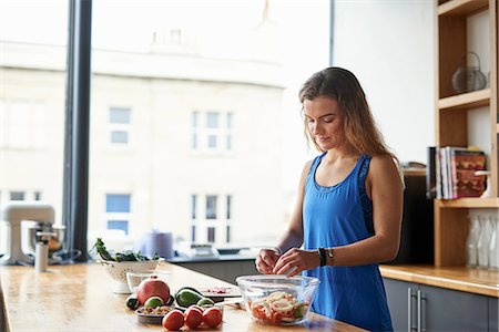 simsearch:649-07559812,k - Young woman at kitchen table preparing salad bowl Stock Photo - Premium Royalty-Free, Code: 649-08969601