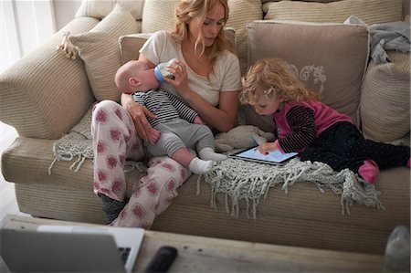 Mother feeding baby son and helping daughter with digital tablet Stock Photo - Premium Royalty-Free, Code: 649-08969858