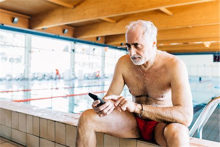 exercise senior man - Senior man using mobile phone by edge of swimming pool Stock Photo - Premium Royalty-Free, Code: 649-08969919