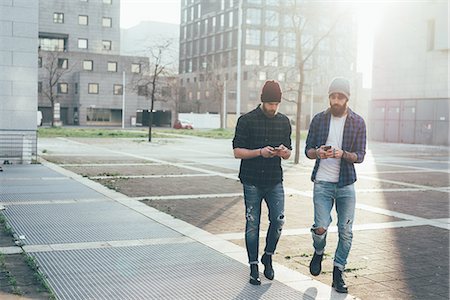 simsearch:649-09252031,k - Two young male hipsters walking in city while looking at smartphones Stock Photo - Premium Royalty-Free, Code: 649-08969960