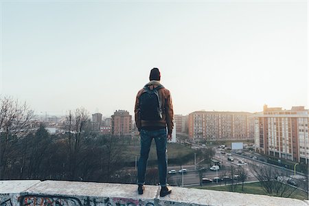 simsearch:649-08702807,k - Rear view of young male hipster standing on city wall looking out Photographie de stock - Premium Libres de Droits, Code: 649-08969970