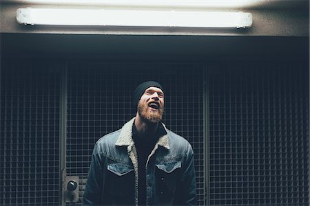 people dim light - Young male hipster laughing in dark city doorway at night Stock Photo - Premium Royalty-Free, Code: 649-08969988